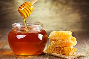 Honig im Glas auf Holztisch angerichtet mit Honigwaben